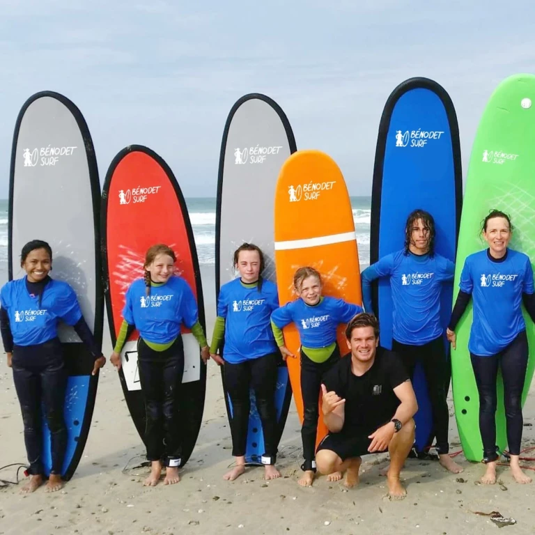 Groupe d'élèves surfeurs avec leur moniteur prenant la pause devant leurs planches