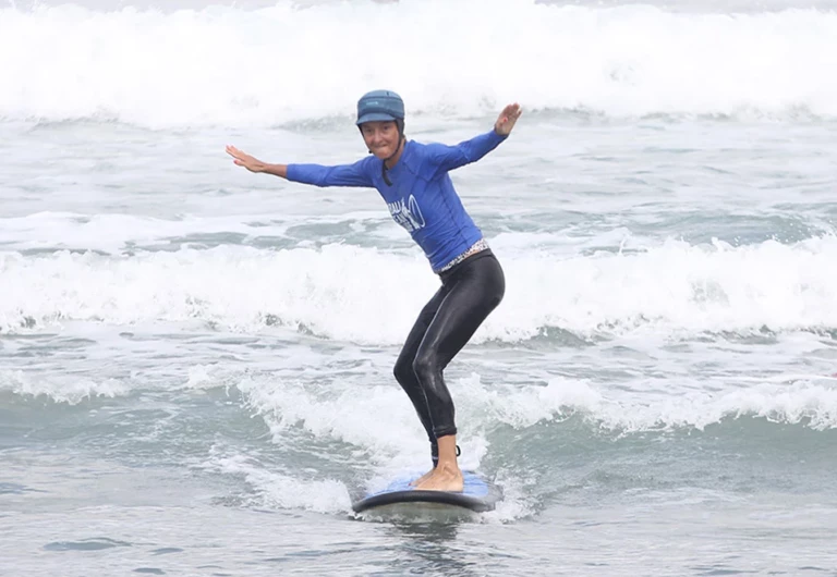 Elève surfant une petite vague avec un grand sourire pendant initiation à la carte