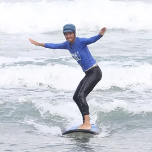 Elève surfant une petite vague avec un grand sourire pendant initiation à la carte