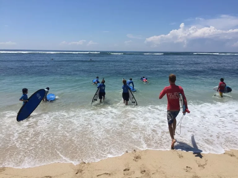 Stagiaires et moniteur courant dans l'eau pour passer les vagues