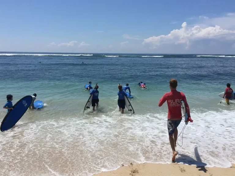 Stagiaires et moniteur courant dans l'eau pour passer les vagues