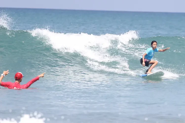 enfant en cours de surf avec un moniteur à Bali